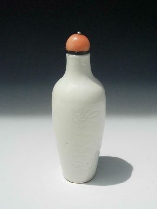 An Antique Chinese Incised White Glazed Porcelain Snuff Bottle And Coral Stopper