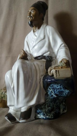 Chinese ceramic mudman statue of a man sitting on a rock with an axe behind him. 3