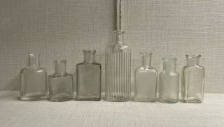 Seven Small Different Old Plain Clear Glass Bottles.