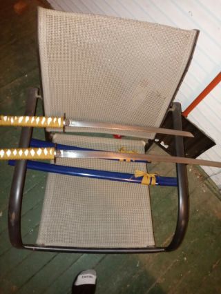 2 Blue Katana Swords With White Handle And Gold Fabric Wrapped Around Them